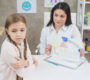 angry blonde little girl looking drawing paper shown by her psychologist 90x80