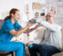 senior man nursing home with doing physical therapy with help from nurse using dumbbells 90x80